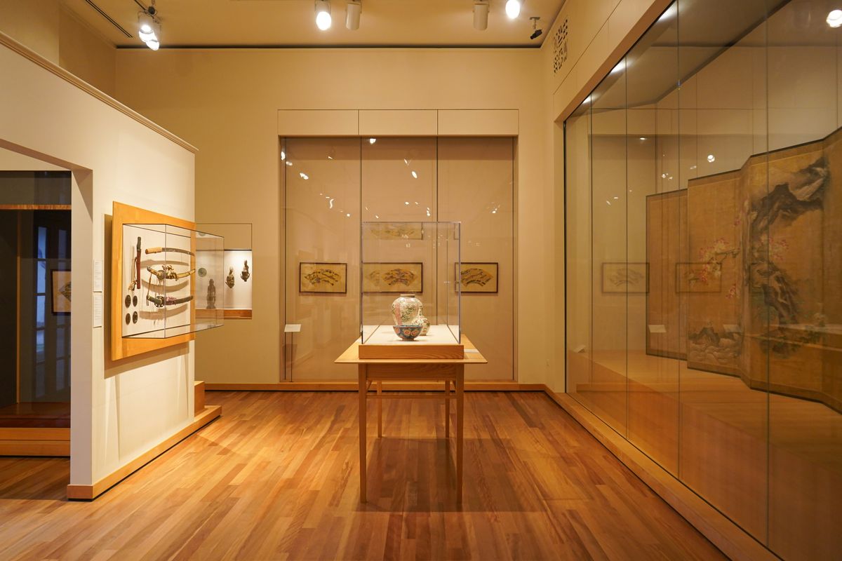 Een vitrine met een vaas op een houten tafel in een tentoonstellingszaal