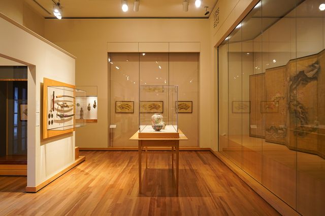 Een vitrine met een vaas op een houten tafel in een tentoonstellingszaal
