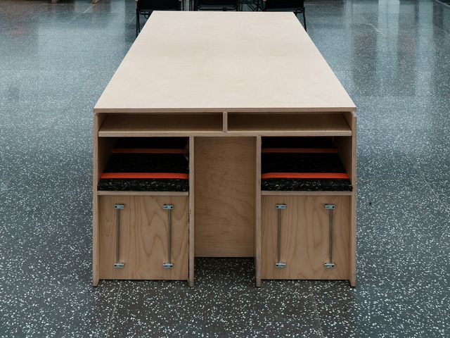 Een presentatietafel in multiplex met vakken en lades in een lichte winkelruimte
